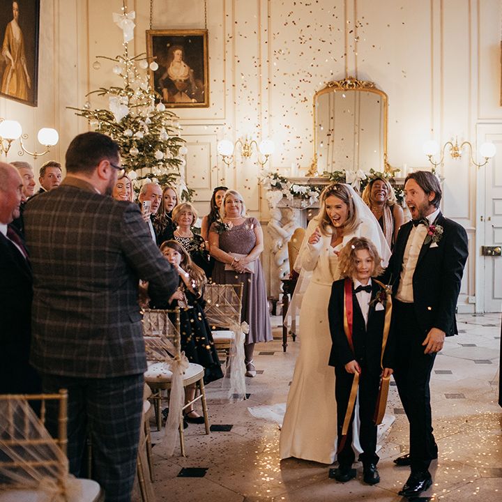 Bride & groom walk down the aisle with their song as confetti cannon explodes around them with gold confetti 