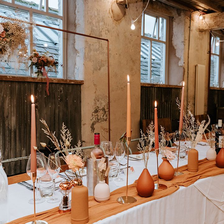 Handpainted terracotta and nude vases with matching coloured candles table setting for industrial wedding venue 