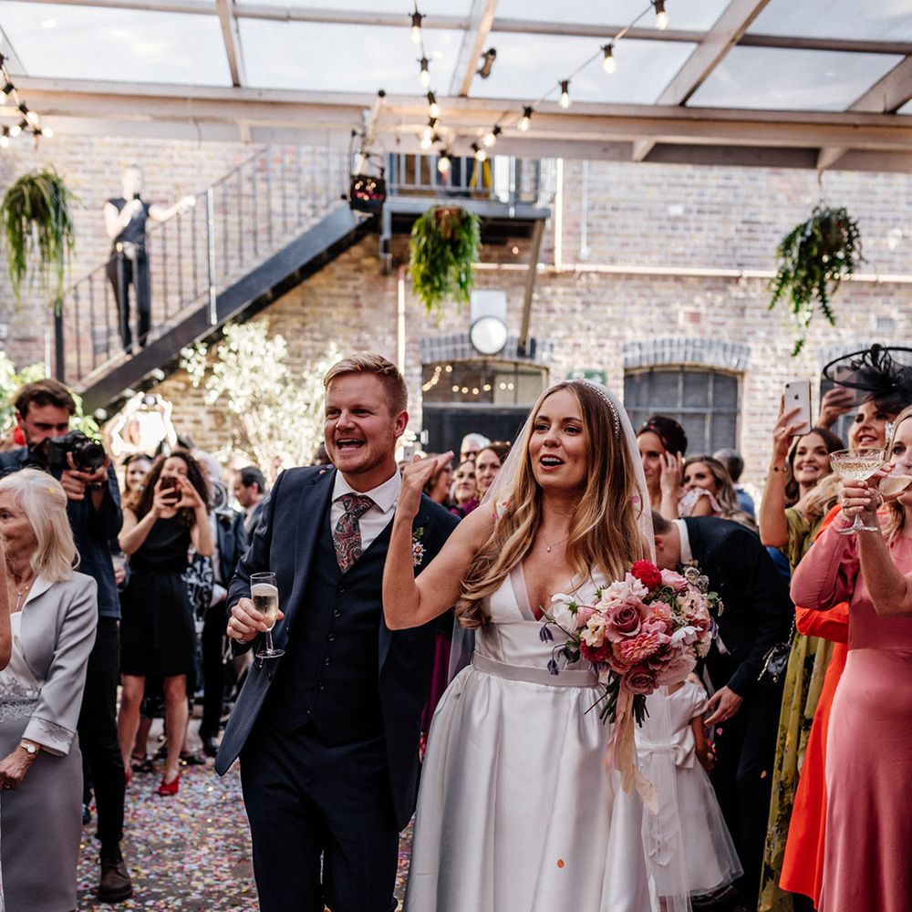 Groom in a three piece navy suit and bride in a Karen Willis Holmes wedding dress with pockets smiling during the wedding speeches 