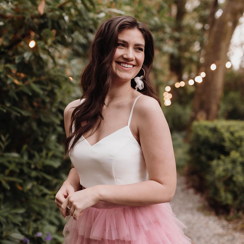 Bride with long wavy hair in a white top and pink skirt bridal separates 