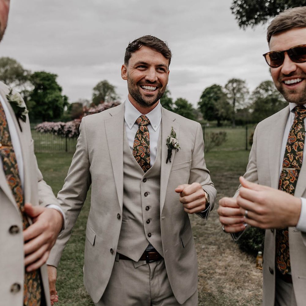 Groom in a three piece stone coloured suit with paisley tie 