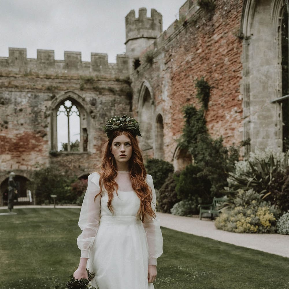 Sustainable bride in a two layer wedding dress and flower crown holding a foliage bridal bouquet in the gardens at Bishop's Palace Wells
