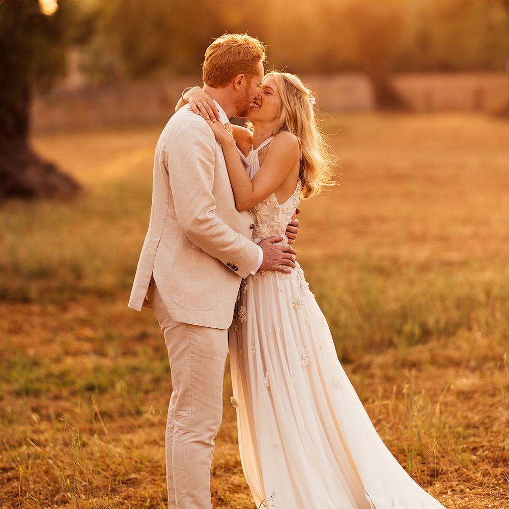 Bride and groom kiss during golden hour for their outdoor destination wedding in summer 