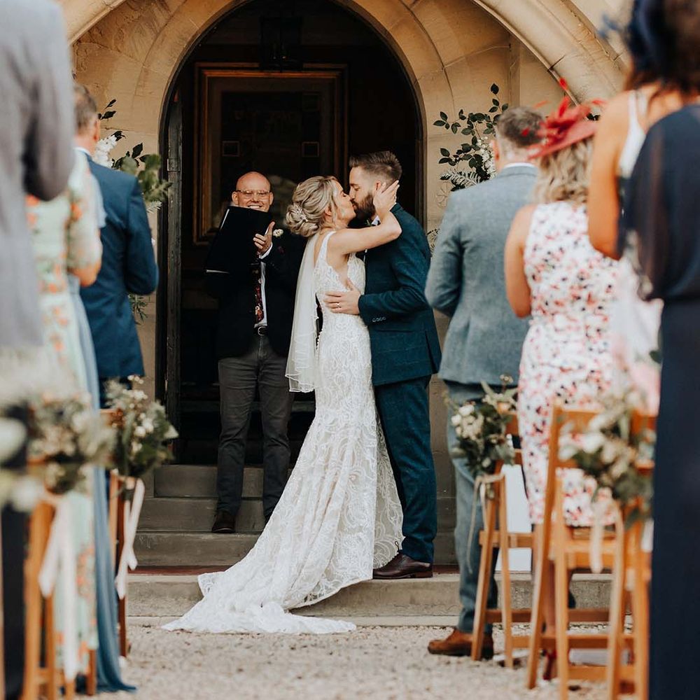 Bride in sleeveless lace detail wedding dress and groom in dark suit kissing at Plas Dinam country house