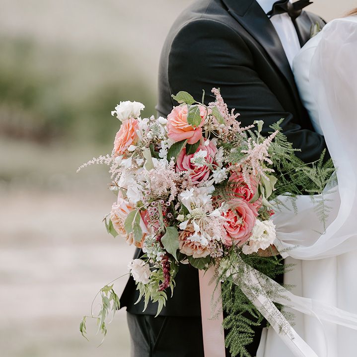 Pastel pink roses in green foliage tied with pink ribbon bridal bouquet