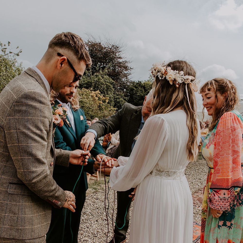 Bride & groom during handfasting ceremony outdoors as bride wears bridal floral crown 