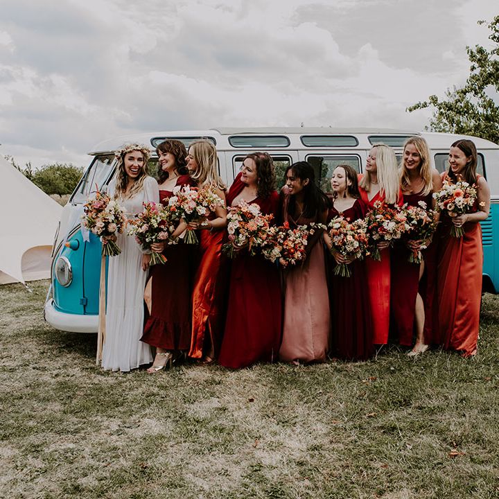 Bride stands with her bridesmaids in Autumnal colour bridesmaid dresses in mismatched styles