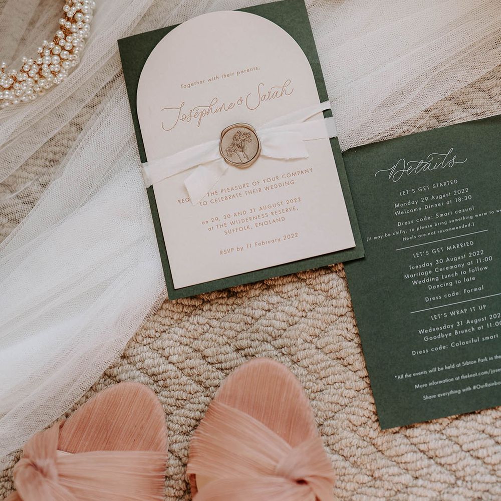 Green and white wedding stationery invitations with ribbon and gol wax seal with the bride's veil, perfume, and pearl headband 