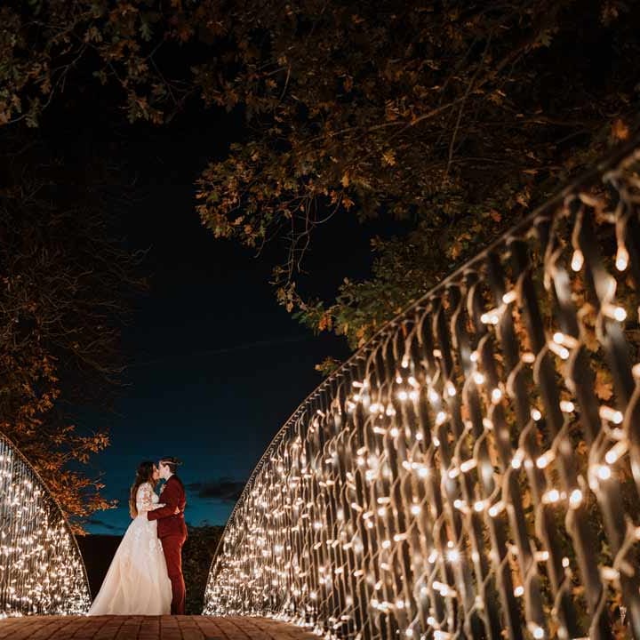 Brides kissing on bride with fairy lights at Bassmead Manor Barns wedding venue Cambridgeshire 