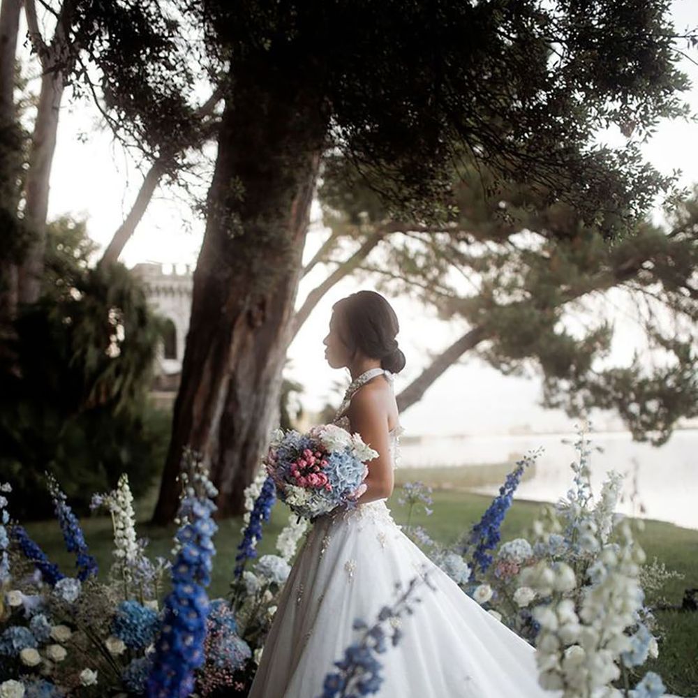 Bride walking down the aisle decorated with blue bell flowers at outdoor destination wedding 