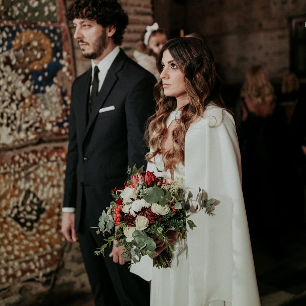 The bride and groom a their church ceremony, the bride is wearing a Nadia Rapti gown and wedding cape