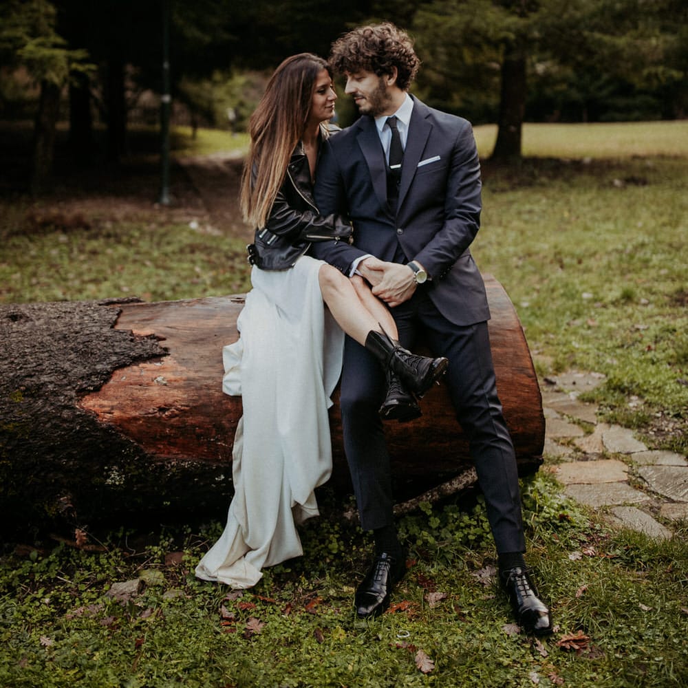 The bride and groom cuddling outside on a fallen tree stump