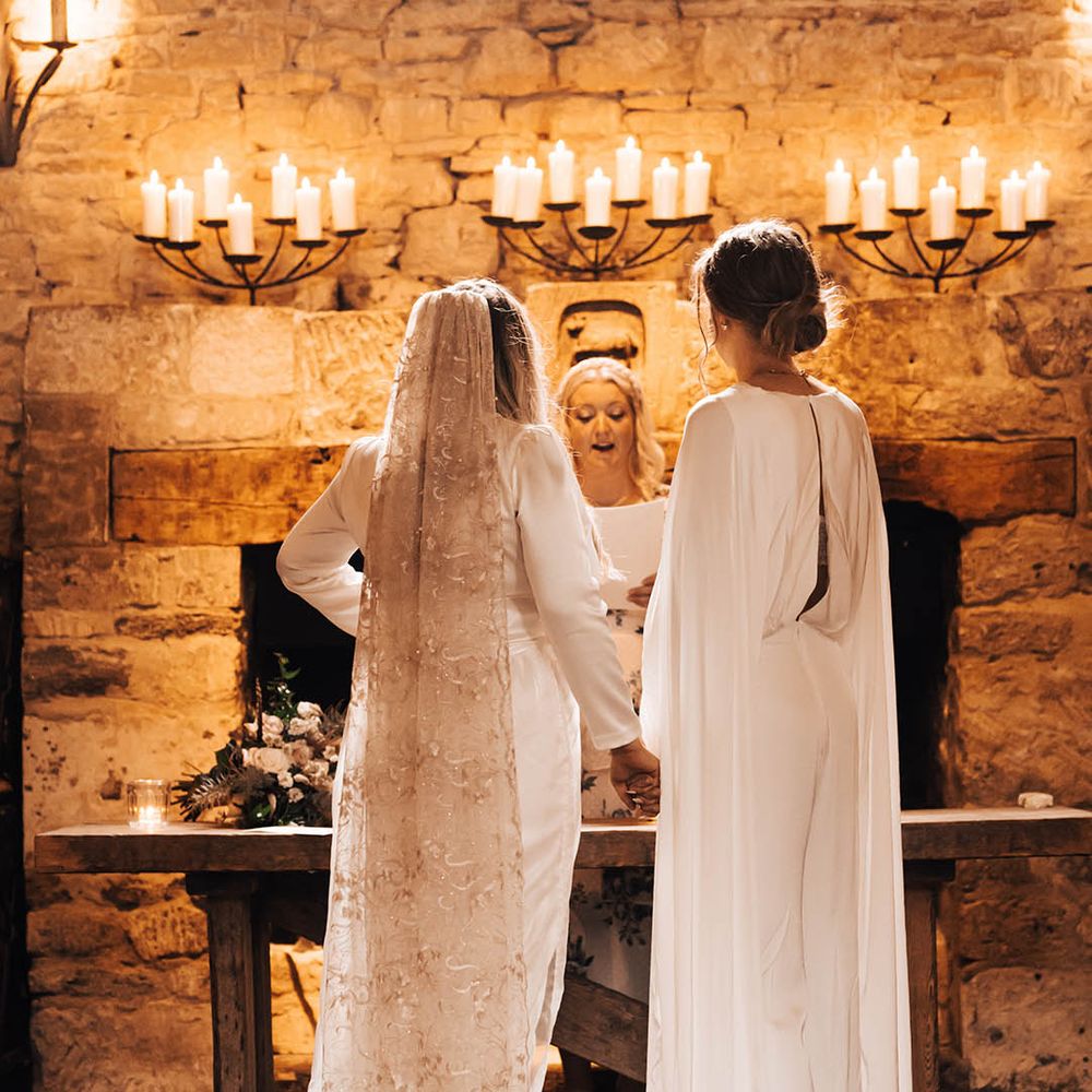 Brides look lovingly at one another on their wedding day during ceremony