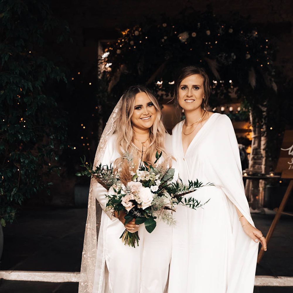 Blonde bride carries white floral bouquet with green foliage
