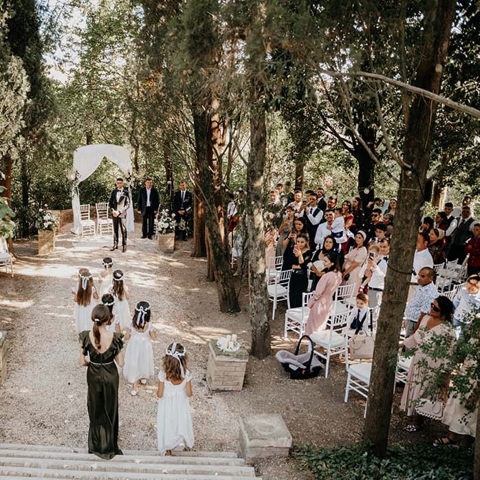 Flower girls walk down the aisle whilst wearing floral headbands for outdoor Italian wedding | Royal Studio