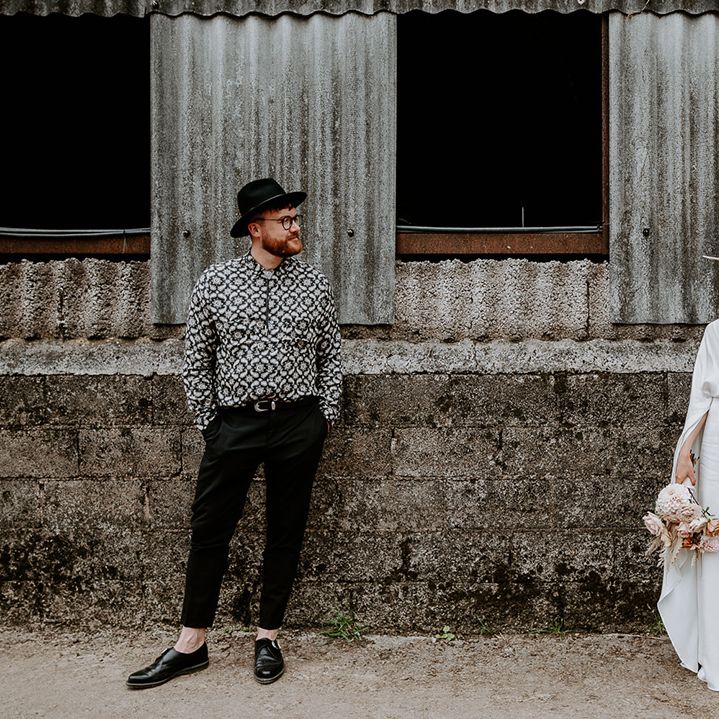 Bride & groom stand apart and look lovingly at one another on farm on their wedding day