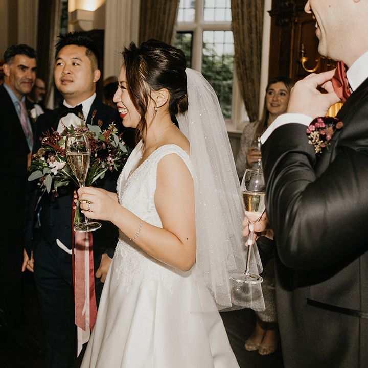 Bride smiles as she sips champagne at winter wedding