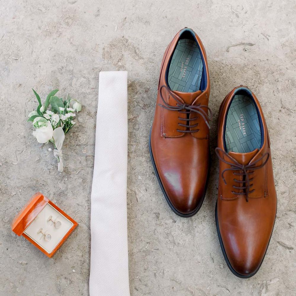 Mens wedding shoes next to cufflinks and floral buttonhole 