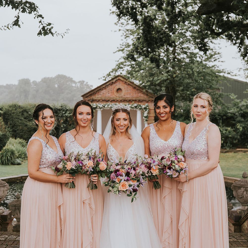 Bride in tulle wedding dress with bridesmaids in blush pink dresses with sequinned tops at country house venue
