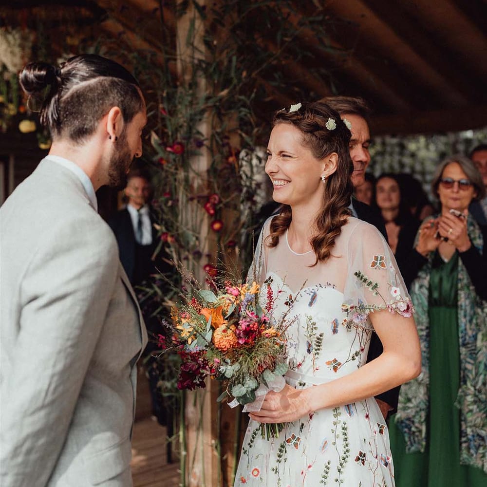 Smiling bride in flower embroidery dress with flower hair accessories and colourful wedding bouquet 