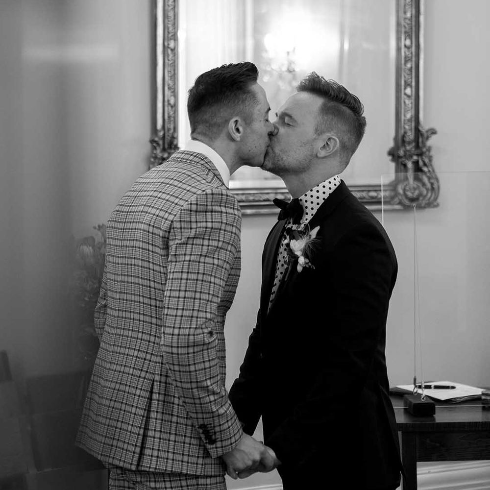 Grooms kiss on their wedding day in black & white image