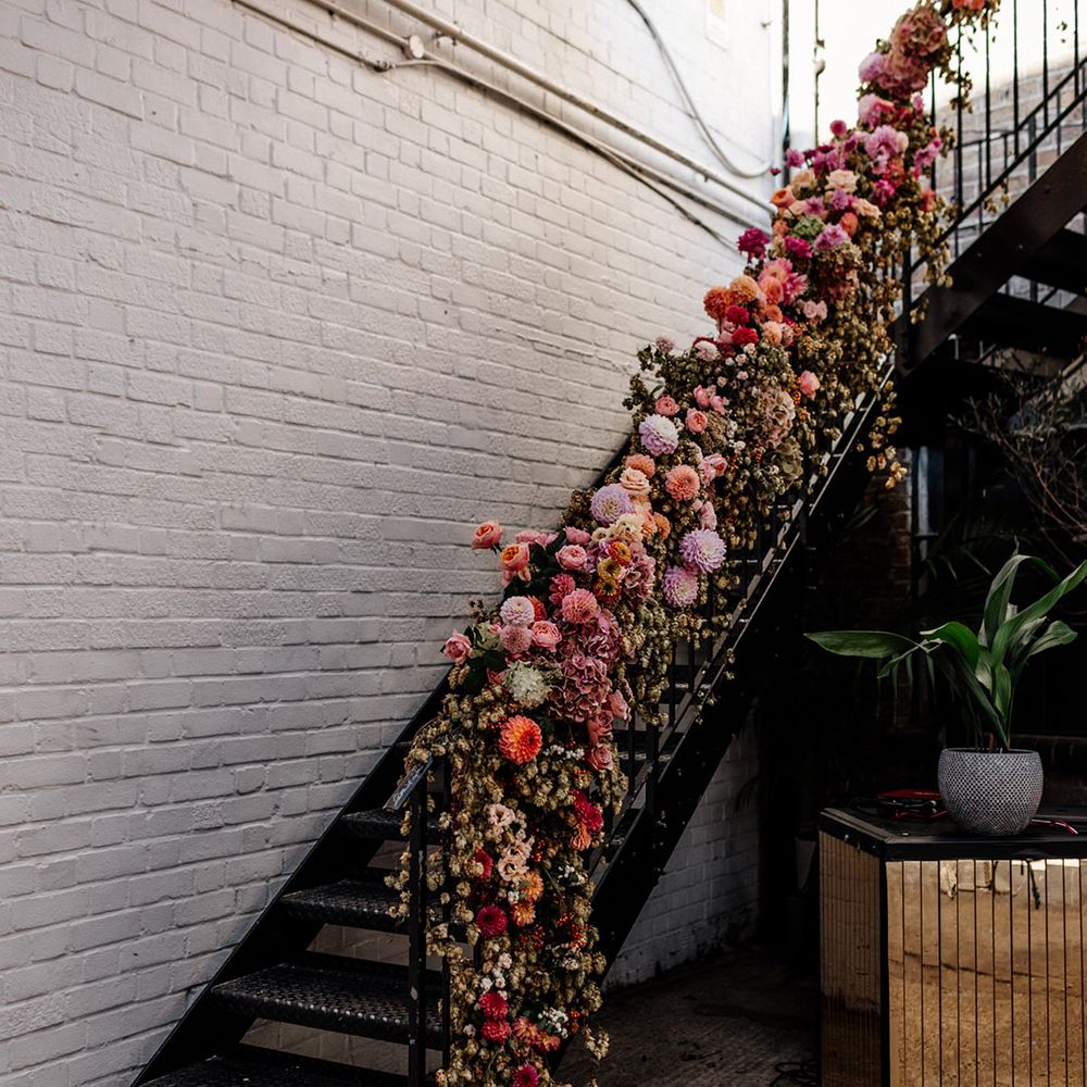 Staircase wedding flower arrangement with green crops and pink and lilac dahlias 