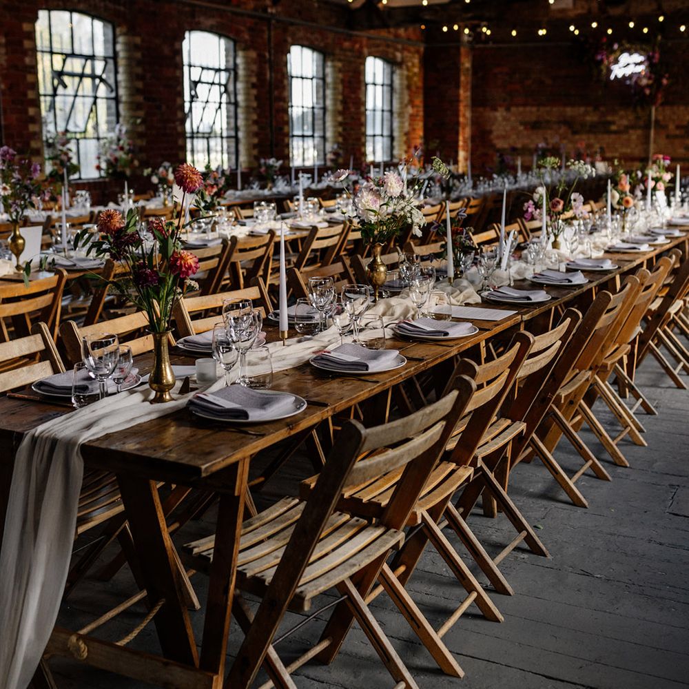 Wedding reception table decor with gold candlesticks and taper candles and flowers stems in vases 