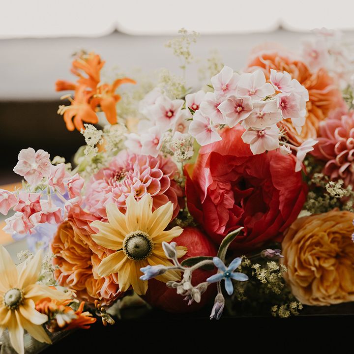 Colourful pink, yellow, blue, orange, and red flowers including white lace flower, carnations and dahlias