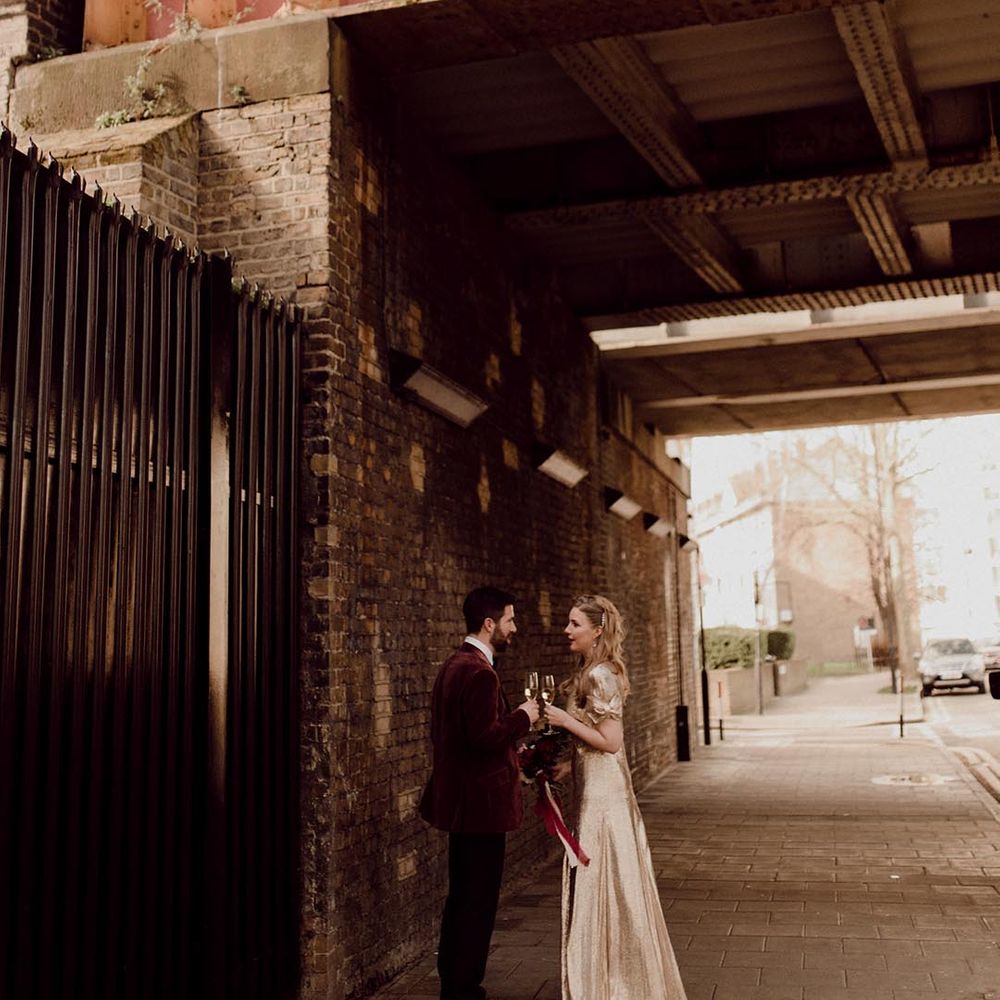 Bride and groom stand drinking outside their city wedding venue