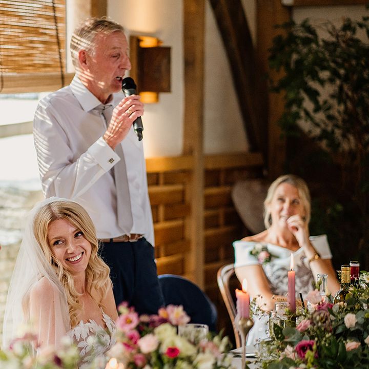 Bride and groom laugh as the father of the bride reads out his speech