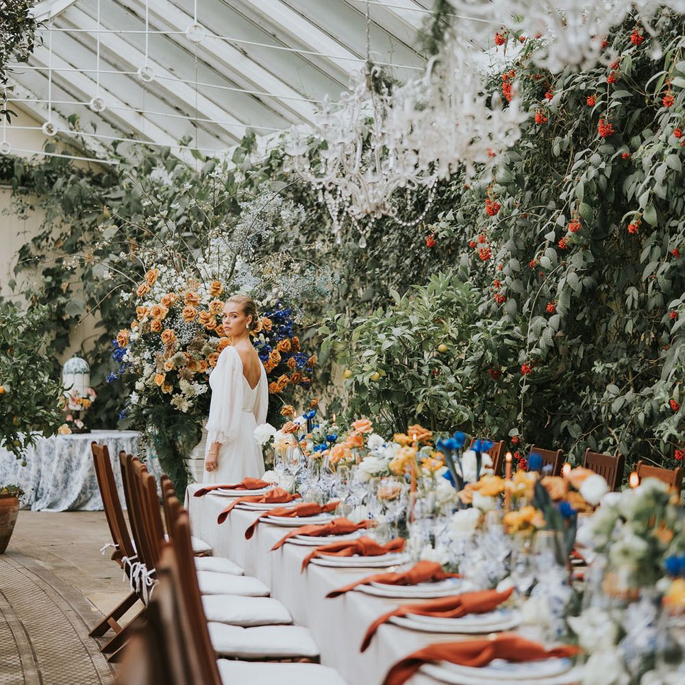 Blue and orange colour scheme wedding tablescape with chandeliers with the bride in a romantic wedding dress