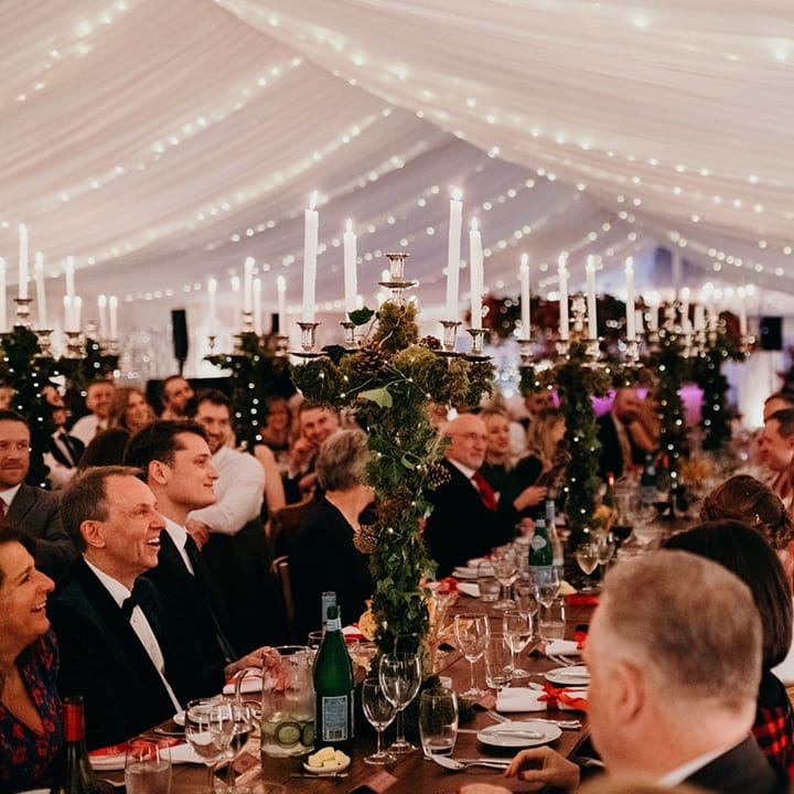 Guests giving speeches at Christmas themed wedding reception with winter foliage decorated candle holders
