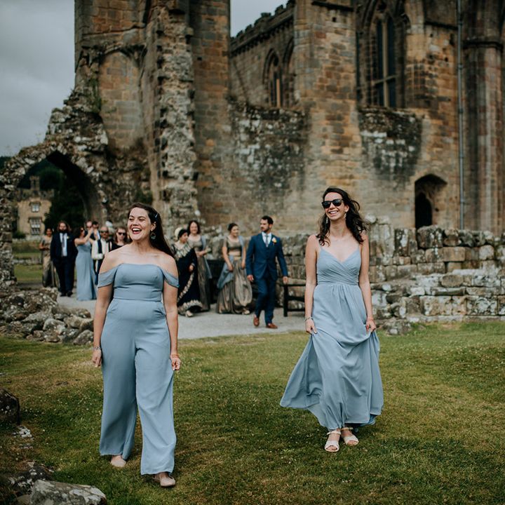 Bridesmaid wears baby blue dress with off the shoulder styling, alongside bridesmaid in baby blue jumpsuit 