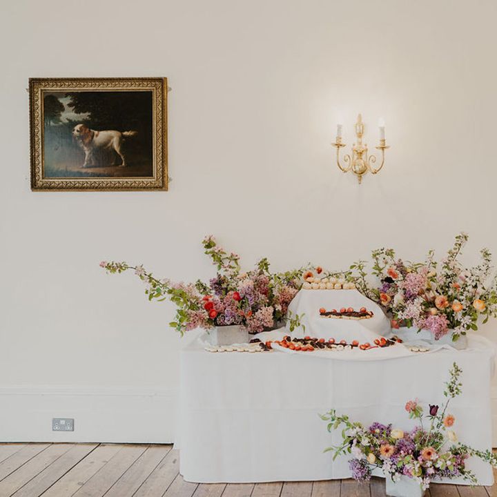 Brightly coloured florals surrounded dessert table 