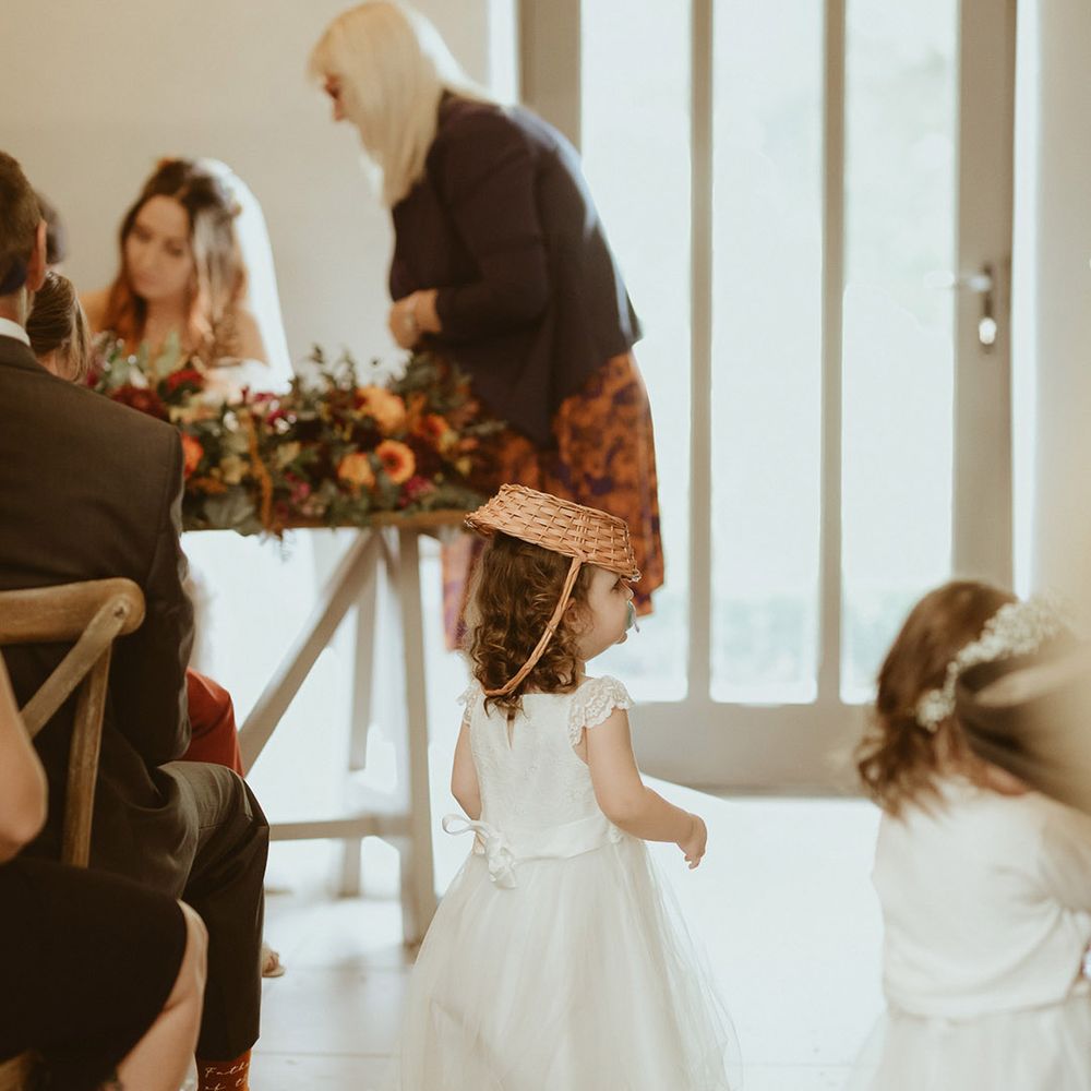 Flower girl in white tulle dress with dummy and wicker basket for the flowers on her head 