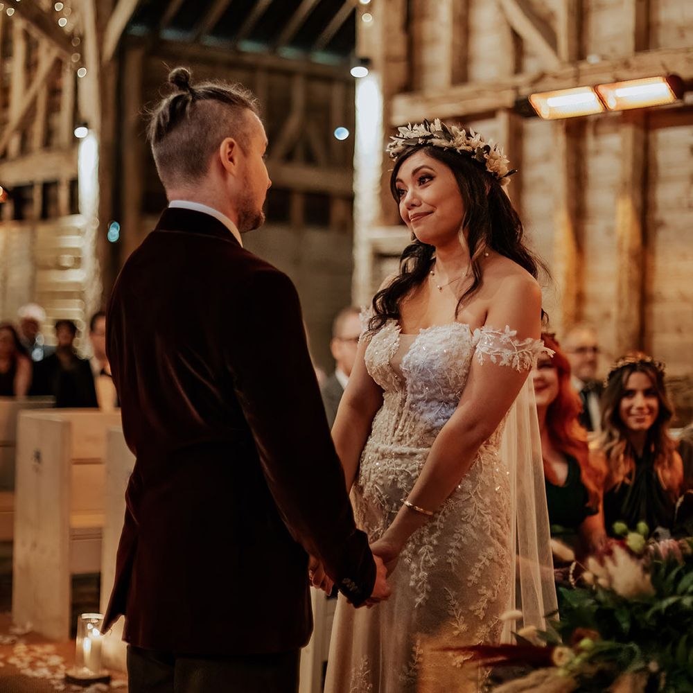 Fairy lit Milling Barn rustic barn wedding venue in Hertfordshire with the bride and groom holding hands for the wedding ceremony