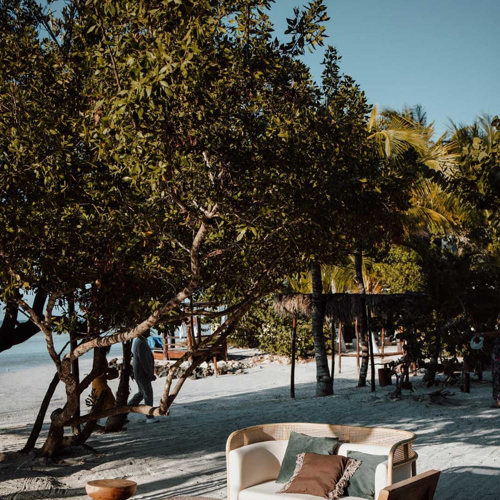 Cream love seat, two wooden stools and wooden chair wedding furniture on destination beach wedding 