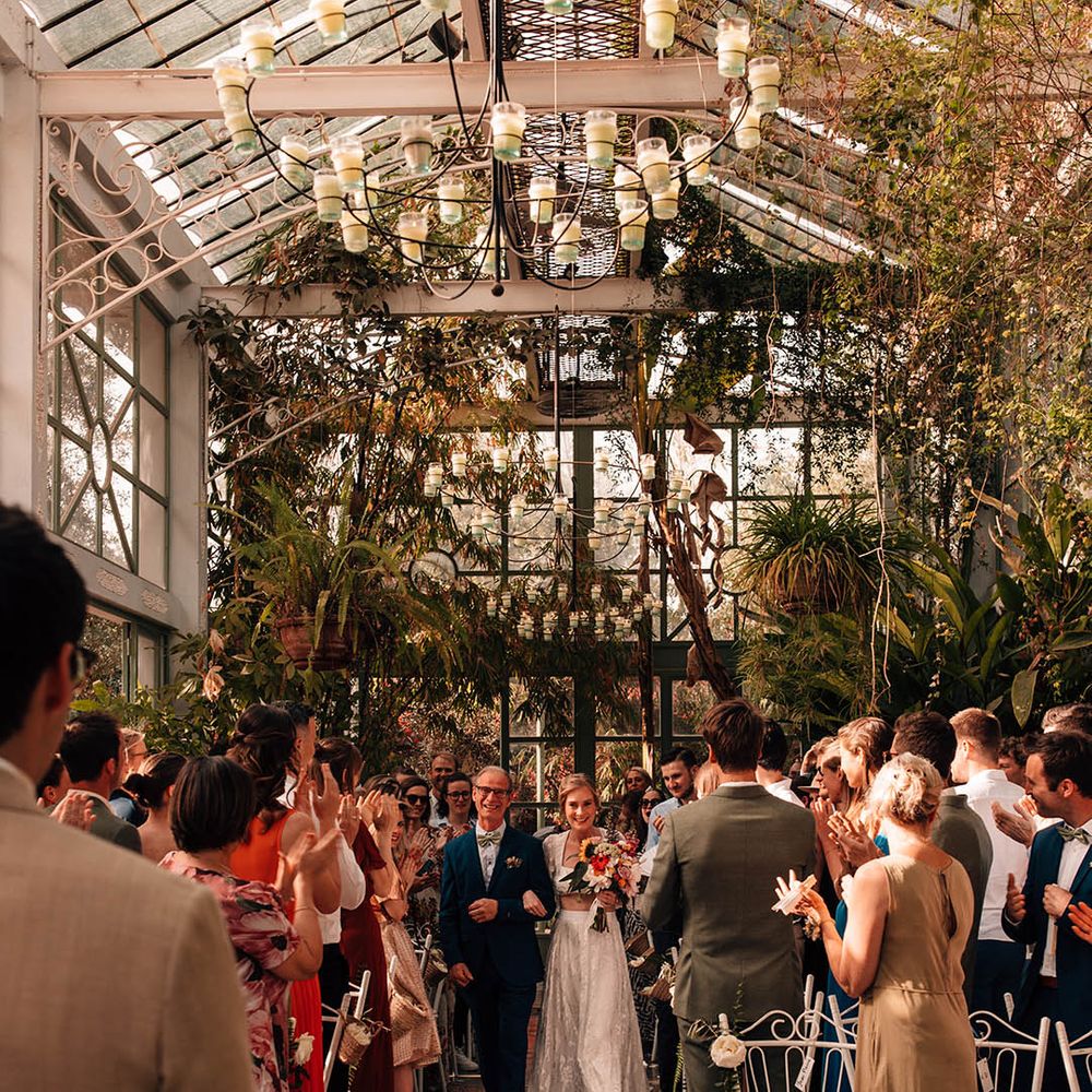Father of the bride in a blue suit walking the bride down the aisle at the glasshouse wedding venue in Morocco 
