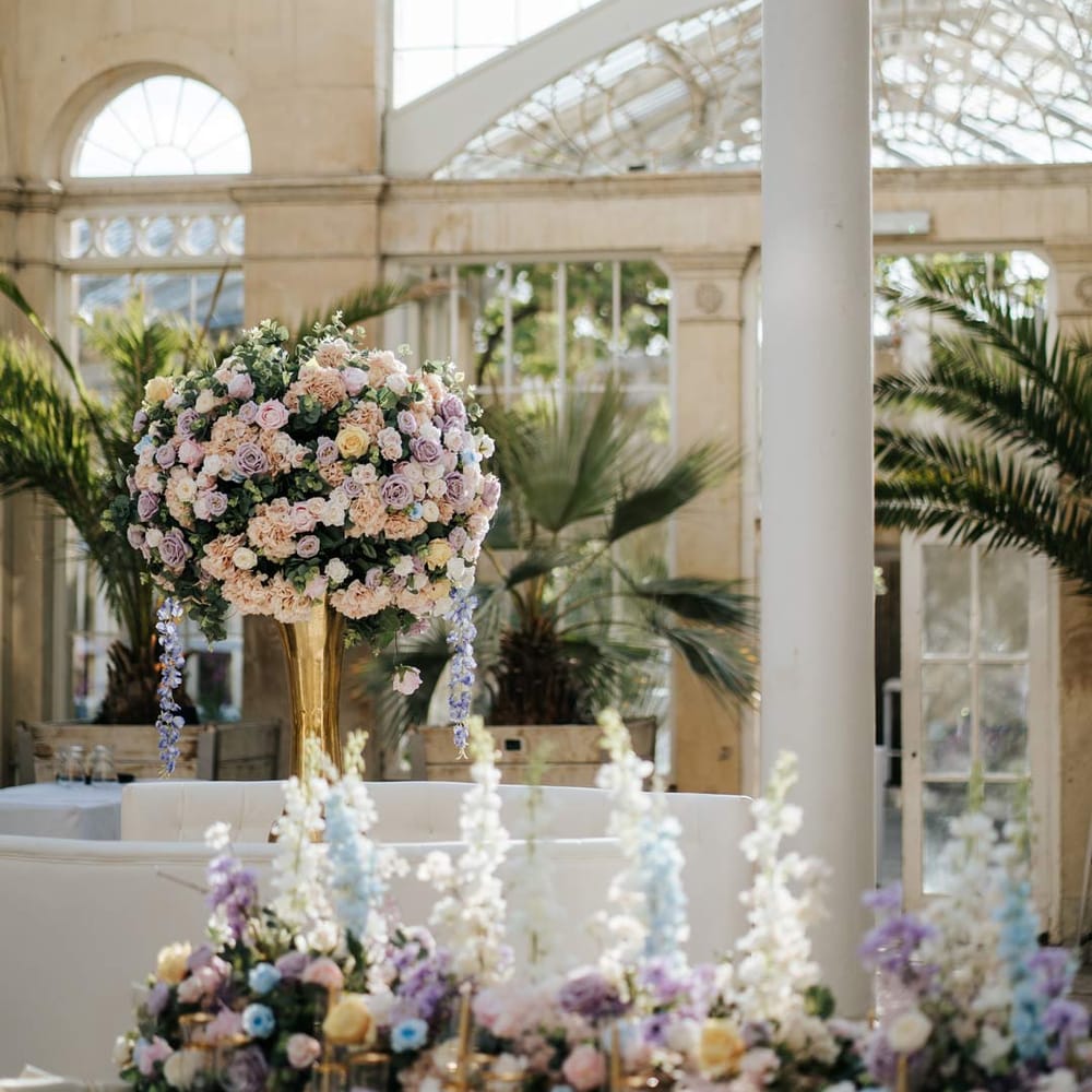 Syon Park wedding venue reception room with suspended pastel florals and tropical plants 