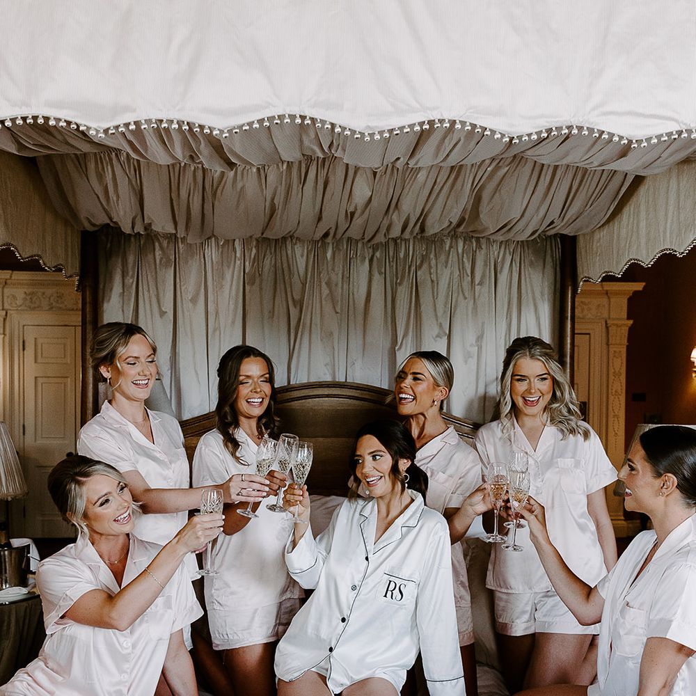 Bridesmaids and bride wearing pyjamas cheers together for hen party 