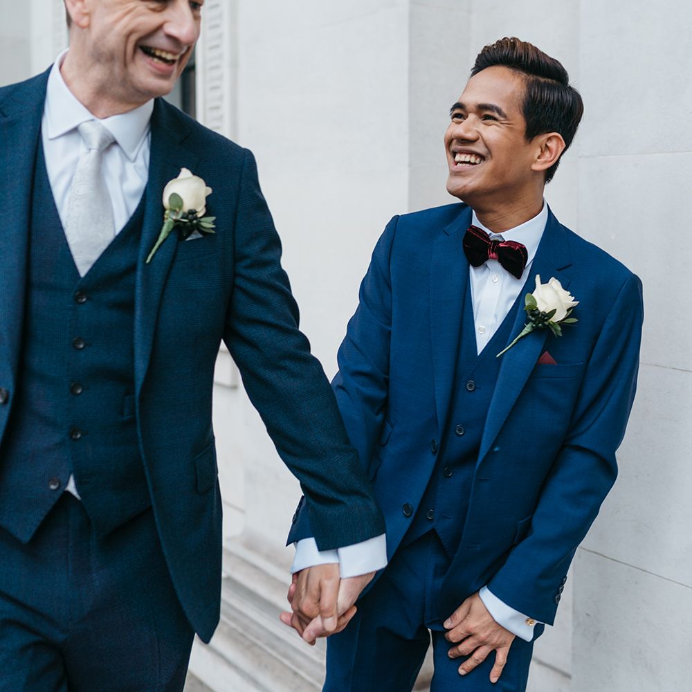 Grooms hold hands and laugh 
