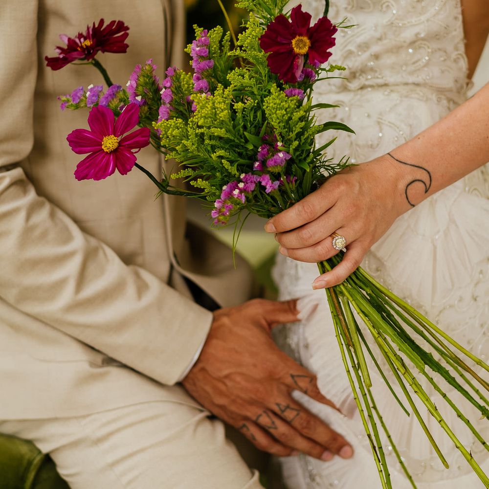 Bride wearing a diamond a yellow gemstone engagement ring holding a wildflower bouquet 