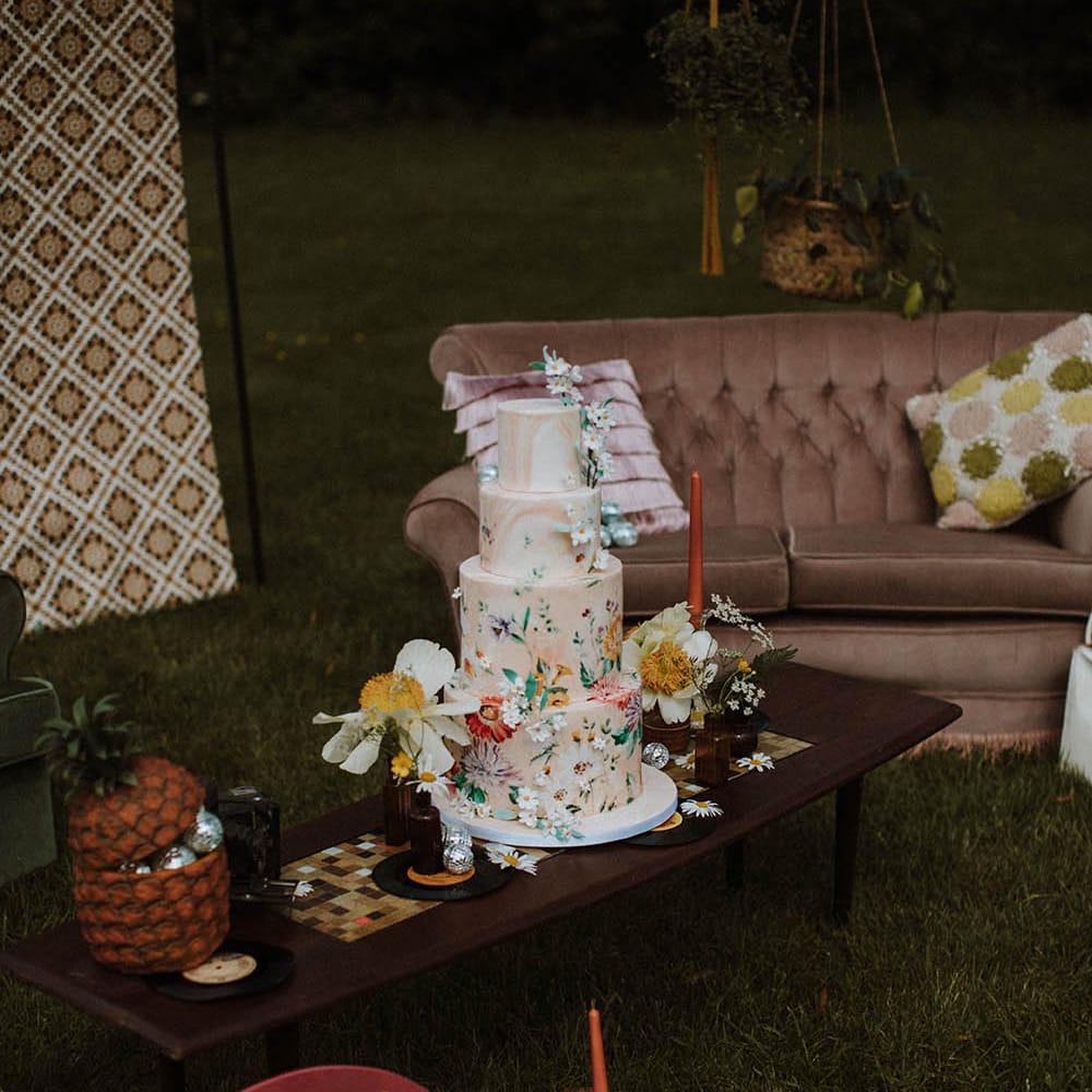 Marble wedding cake with wildflower illustration resting on a retro coffee table 