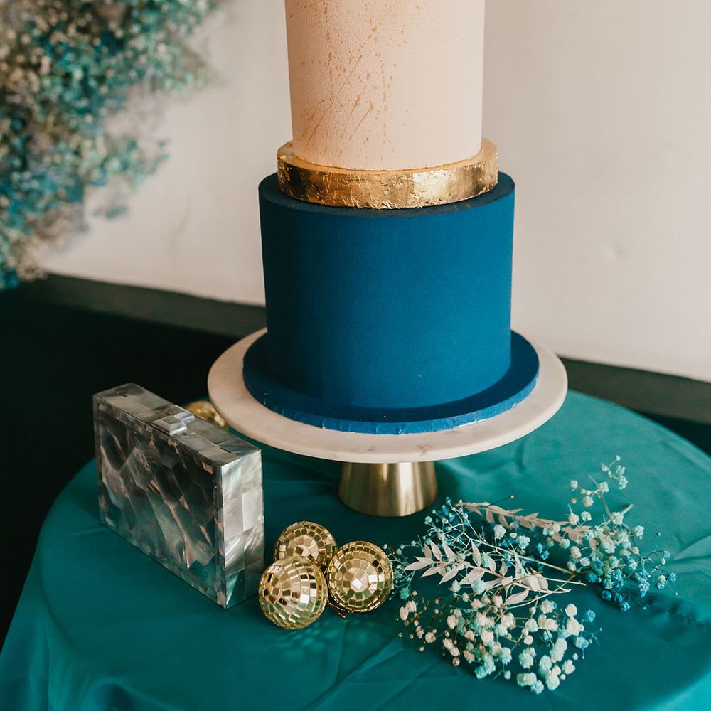 Three tier buttercream wedding cake with teal, cream and white layers and a sugar shard cake topper 