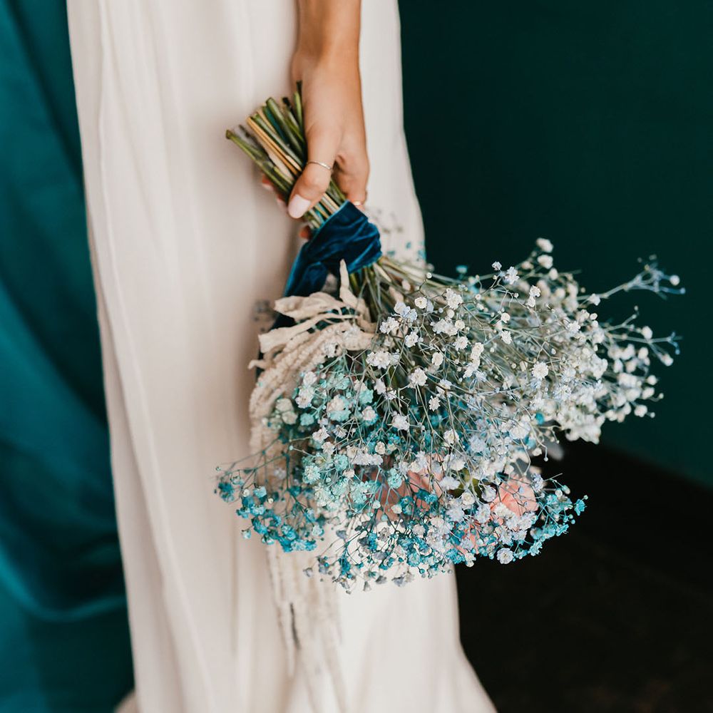 Bride with white wedding nails holding her white and teal gypsophila bouquet down by her side 