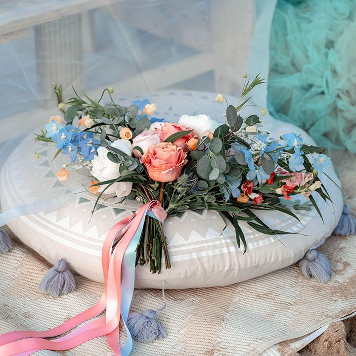 Pastel wedding bouquet with coral roses, eucalyptus foliage and white peonies tied with ribbon 