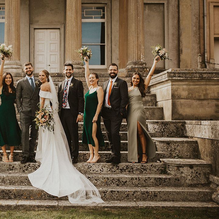 Bride & groom celebrate with their wedding party on the staircase of wedding venue outdoors 