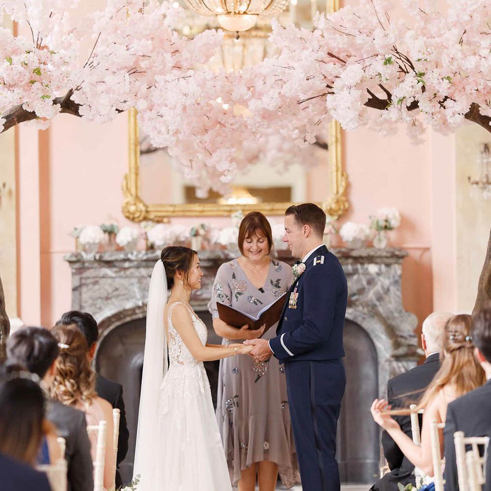 Bride & groom hold hands during wedding ceremony as celebrant reads 