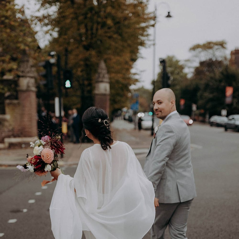 Grooms holds his brides hand as they walk with one another after wedding ceremony