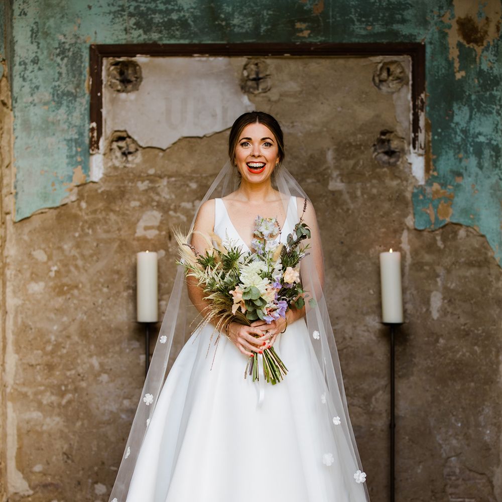 Smiling bride in white wedding gown wearing veil with 3D flower detail